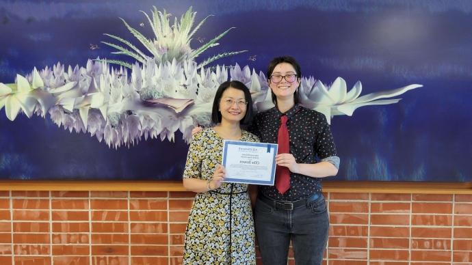 A student and a faculty member pose for a photo with an award.