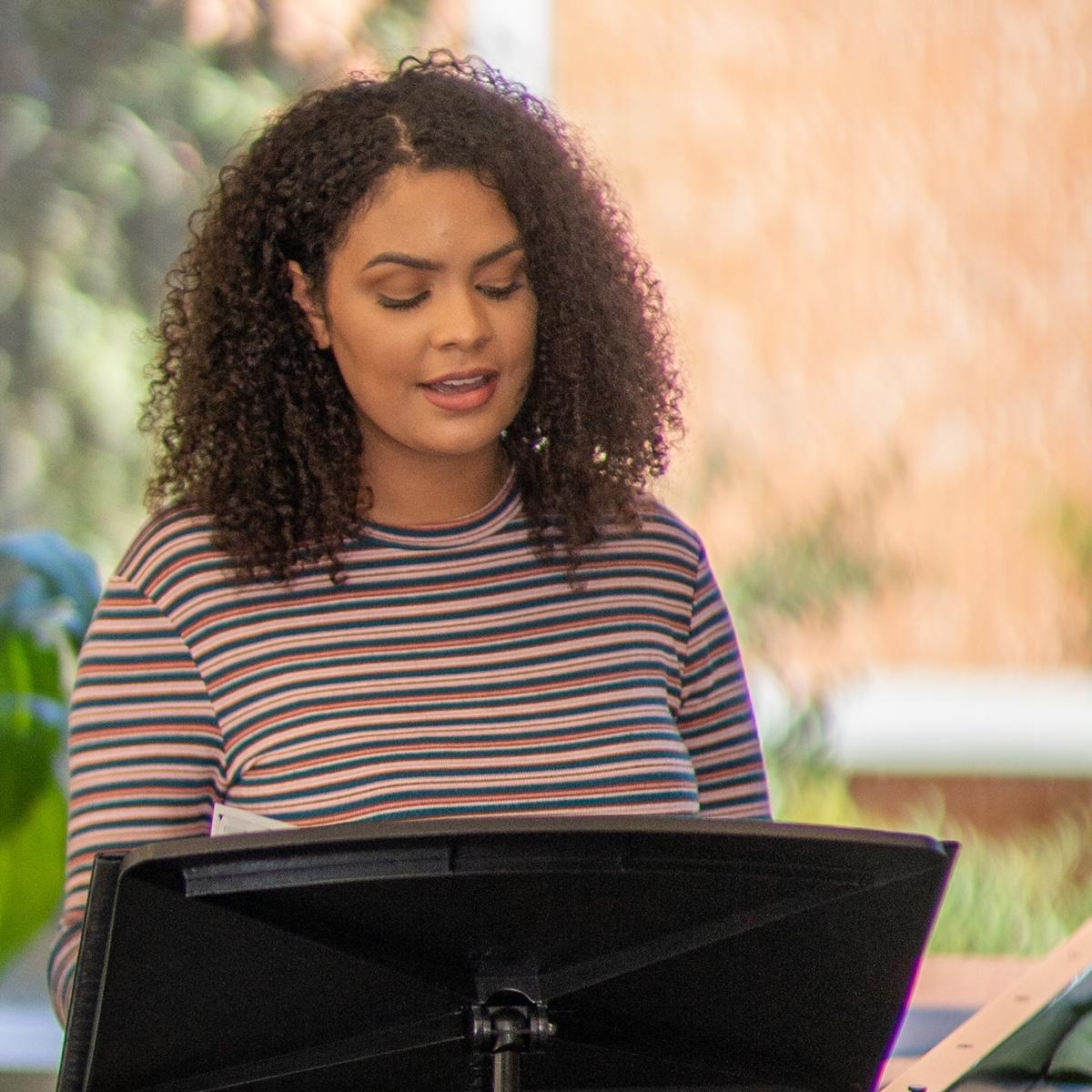 Caelia Marshall sings with sheet music on a music st和 in a faculty rehearsal space